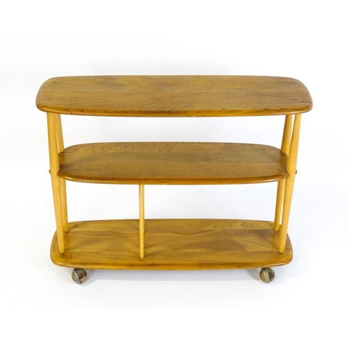 1650 - Vintage / Retro: An Ercol elm trolley with three shaped tiers on four turned supports and raised on ... 