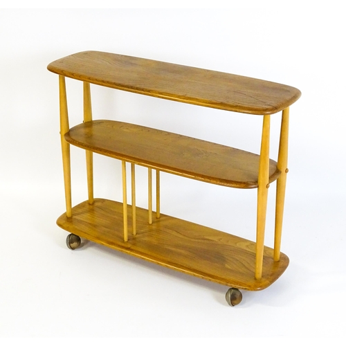 1650 - Vintage / Retro: An Ercol elm trolley with three shaped tiers on four turned supports and raised on ... 