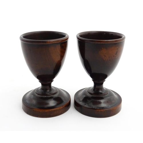 1129 - Treen : A pair of turned wooden egg cups of pedestal form. Approx. 2 3/4