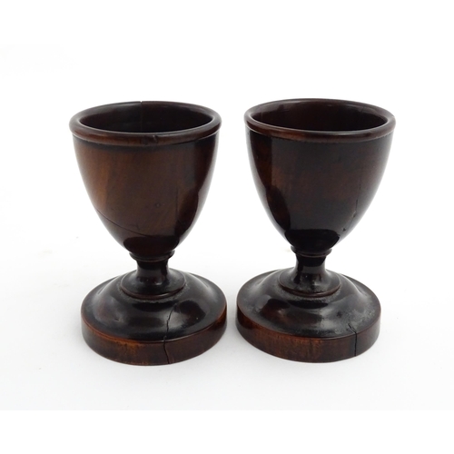 1129 - Treen : A pair of turned wooden egg cups of pedestal form. Approx. 2 3/4