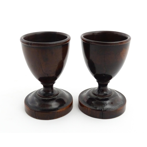 1129 - Treen : A pair of turned wooden egg cups of pedestal form. Approx. 2 3/4