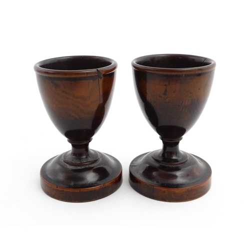 1129 - Treen : A pair of turned wooden egg cups of pedestal form. Approx. 2 3/4