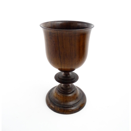 1182 - Treen : A 19thC turned wooden pedestal cup of goblet form. Bears remains of old collector label unde... 