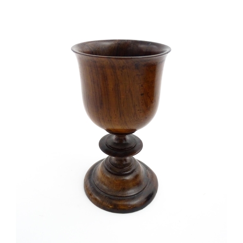 1182 - Treen : A 19thC turned wooden pedestal cup of goblet form. Bears remains of old collector label unde... 