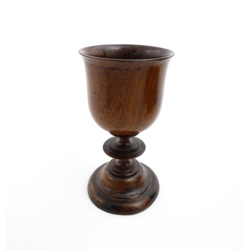 1182 - Treen : A 19thC turned wooden pedestal cup of goblet form. Bears remains of old collector label unde... 