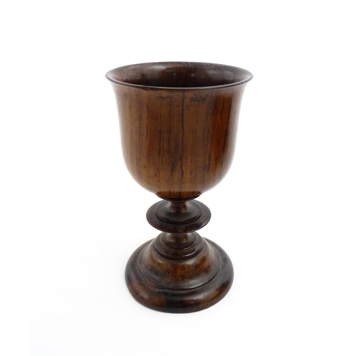 1182 - Treen : A 19thC turned wooden pedestal cup of goblet form. Bears remains of old collector label unde... 