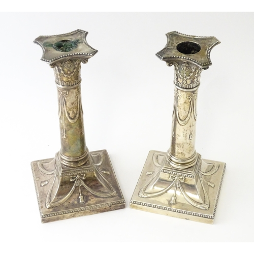 558 - A pair of Geo V silver candlesticks of column form with bow and swag detail hallmarked London 1911, ... 