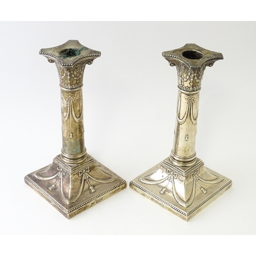 558 - A pair of Geo V silver candlesticks of column form with bow and swag detail hallmarked London 1911, ... 