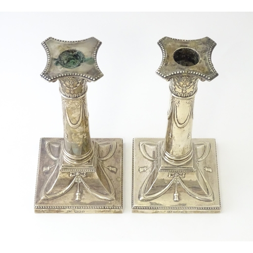 558 - A pair of Geo V silver candlesticks of column form with bow and swag detail hallmarked London 1911, ... 