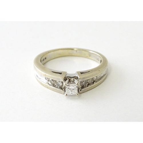 634 - A 14ct white gold ring set with central diamonds flanked by three channel set diamonds to each shoul... 