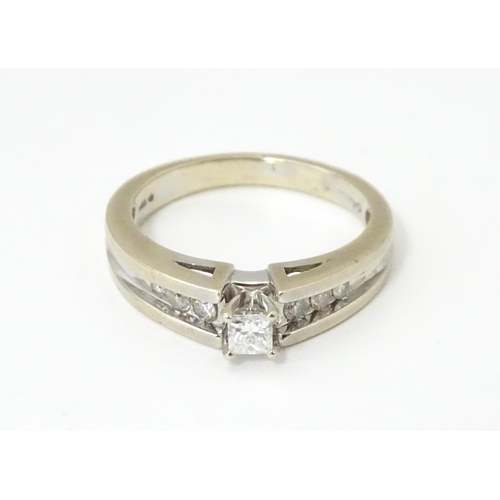 634 - A 14ct white gold ring set with central diamonds flanked by three channel set diamonds to each shoul... 