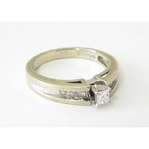 634 - A 14ct white gold ring set with central diamonds flanked by three channel set diamonds to each shoul... 