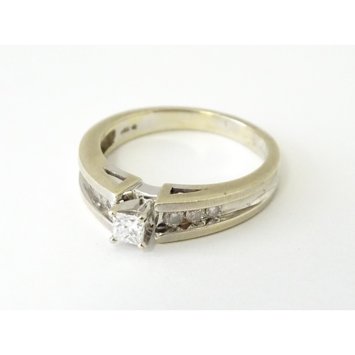 634 - A 14ct white gold ring set with central diamonds flanked by three channel set diamonds to each shoul... 