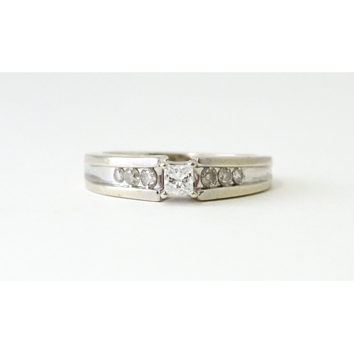 634 - A 14ct white gold ring set with central diamonds flanked by three channel set diamonds to each shoul... 