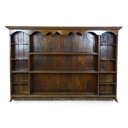 94 - An 18thC oak plate rack with a moulded frieze above two sets of five small shelves flanking three ce... 