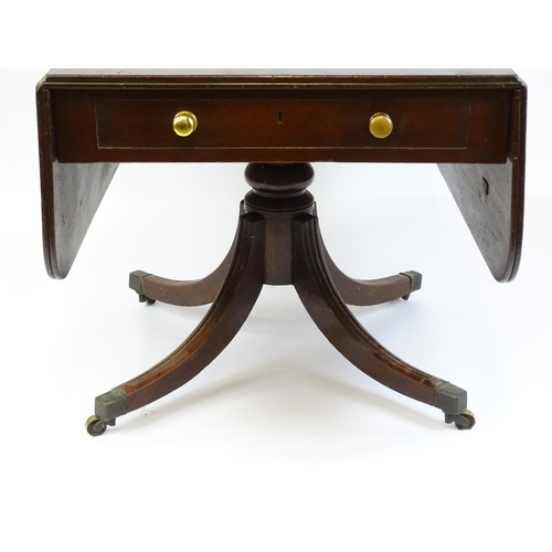 39 - A 19thC mahogany sofa table with two drop leaves above a turned pedestal and four moulded legs termi... 