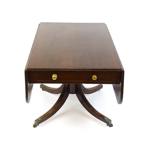 39 - A 19thC mahogany sofa table with two drop leaves above a turned pedestal and four moulded legs termi... 