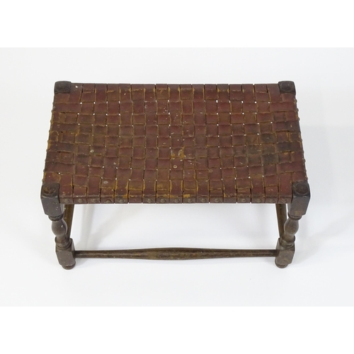 6 - An early / mid 20thC leather pleated footstool raised on four turned tapering legs united by a box s... 