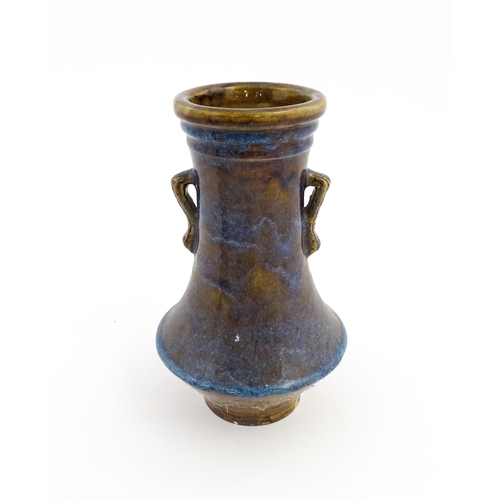 32 - An Oriental twin handled vase with a high fired glaze and banded detail to rim. Approx. 11 14/