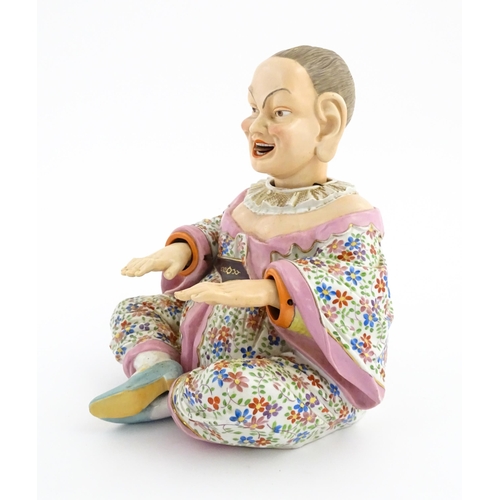 54 - An Ernst Bohne porcelain figure modelled as a seated Chinese / Oriental man with articulated head, t... 