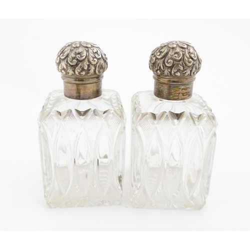 213 - A pair of Victorian cut glass scent bottles of squared form with glass stoppers and silver tops hall... 