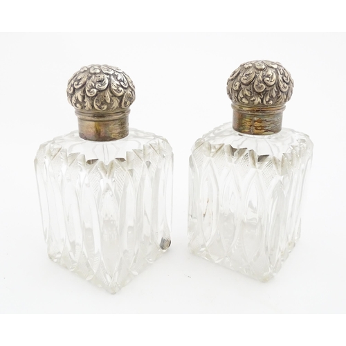 213 - A pair of Victorian cut glass scent bottles of squared form with glass stoppers and silver tops hall... 