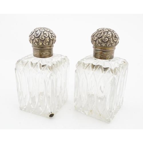 213 - A pair of Victorian cut glass scent bottles of squared form with glass stoppers and silver tops hall... 