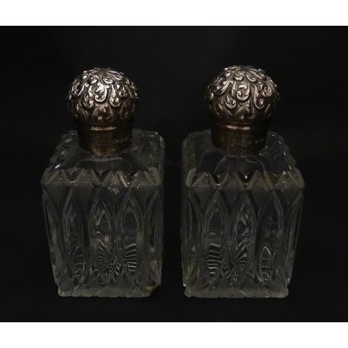 213 - A pair of Victorian cut glass scent bottles of squared form with glass stoppers and silver tops hall... 