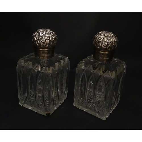 213 - A pair of Victorian cut glass scent bottles of squared form with glass stoppers and silver tops hall... 