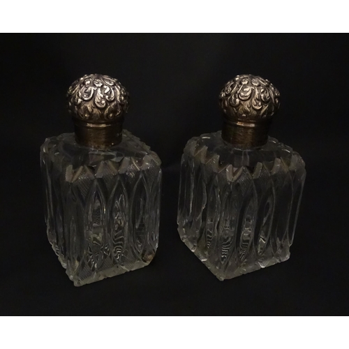 213 - A pair of Victorian cut glass scent bottles of squared form with glass stoppers and silver tops hall... 