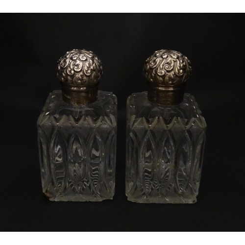 213 - A pair of Victorian cut glass scent bottles of squared form with glass stoppers and silver tops hall... 