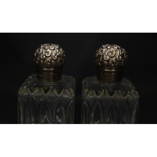 213 - A pair of Victorian cut glass scent bottles of squared form with glass stoppers and silver tops hall... 