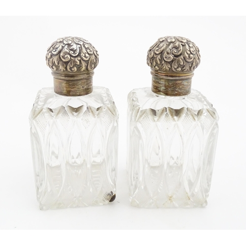 213 - A pair of Victorian cut glass scent bottles of squared form with glass stoppers and silver tops hall... 