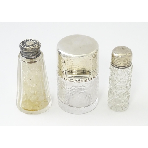 489 - Three various  glass jars / scent bottles with silver lids, one with hammered decoration hallmarked ... 