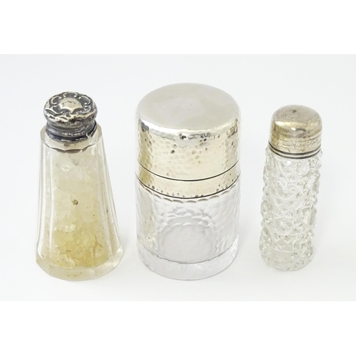 489 - Three various  glass jars / scent bottles with silver lids, one with hammered decoration hallmarked ... 