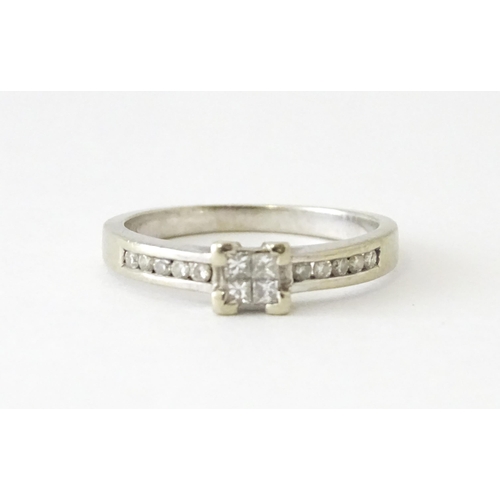 635 - A 9ct white gold ring set with four central diamonds in a square setting, flanked by five channel se... 