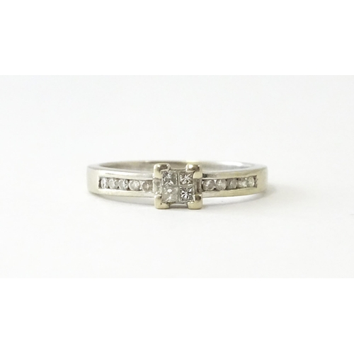 635 - A 9ct white gold ring set with four central diamonds in a square setting, flanked by five channel se... 