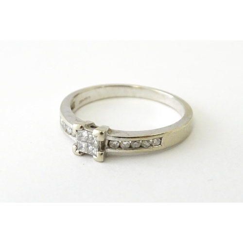 635 - A 9ct white gold ring set with four central diamonds in a square setting, flanked by five channel se... 