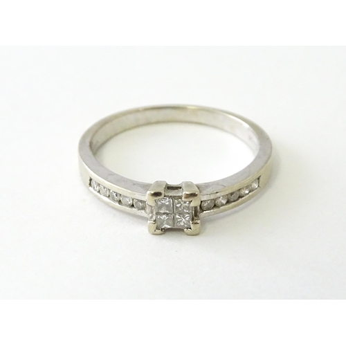 635 - A 9ct white gold ring set with four central diamonds in a square setting, flanked by five channel se... 