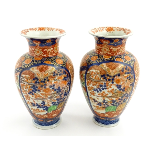 10 - A pair of Japanese vases of baluster form decorated in the Imari palette with flowers and foliage. A... 