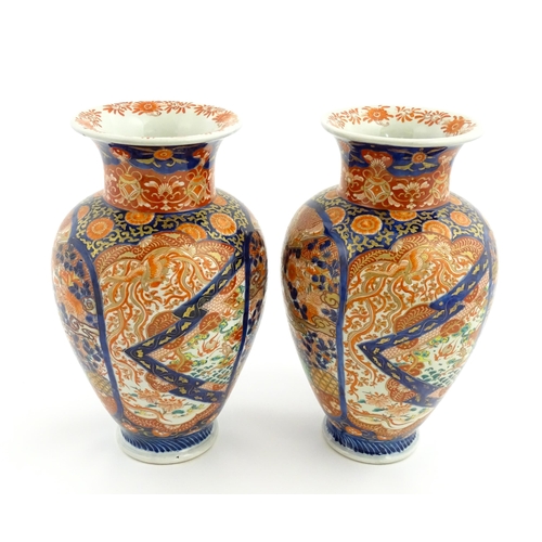 10 - A pair of Japanese vases of baluster form decorated in the Imari palette with flowers and foliage. A... 