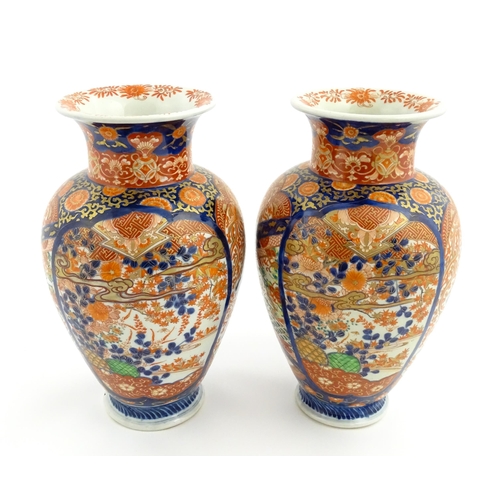 10 - A pair of Japanese vases of baluster form decorated in the Imari palette with flowers and foliage. A... 