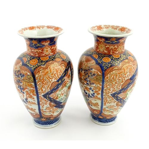 10 - A pair of Japanese vases of baluster form decorated in the Imari palette with flowers and foliage. A... 