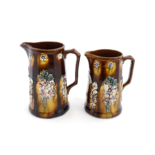 150 - Two Victorian Measham bargeware jugs decorated with flower detail, each bearing a plaque one titled ... 