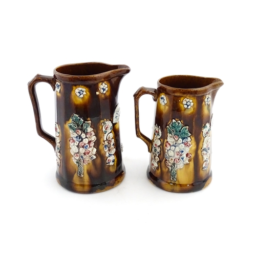 150 - Two Victorian Measham bargeware jugs decorated with flower detail, each bearing a plaque one titled ... 