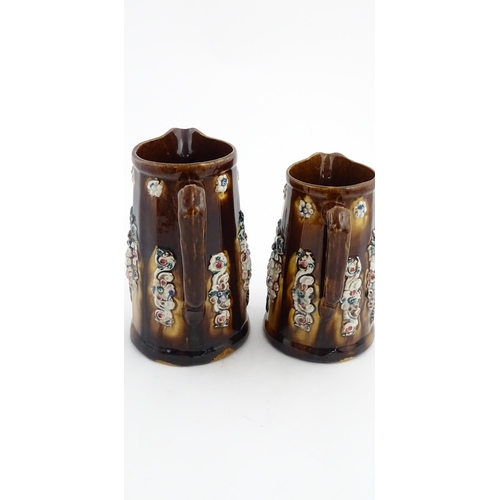 150 - Two Victorian Measham bargeware jugs decorated with flower detail, each bearing a plaque one titled ... 