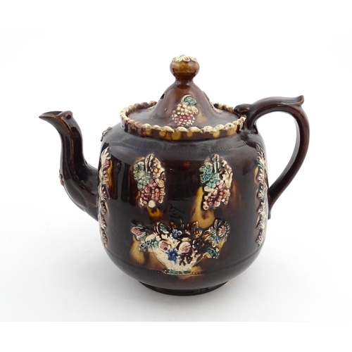 169 - A Victorian Measham bargeware teapot decorated with a basket of flowers, berries, and foliage. Appro... 