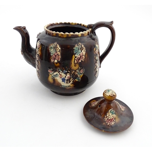 169 - A Victorian Measham bargeware teapot decorated with a basket of flowers, berries, and foliage. Appro... 