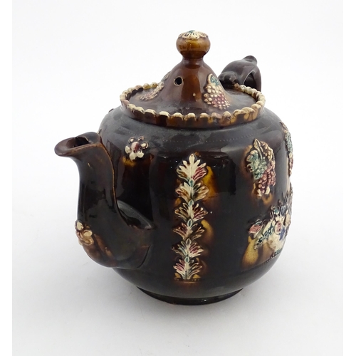 169 - A Victorian Measham bargeware teapot decorated with a basket of flowers, berries, and foliage. Appro... 