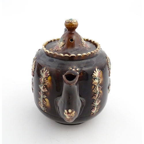 169 - A Victorian Measham bargeware teapot decorated with a basket of flowers, berries, and foliage. Appro... 